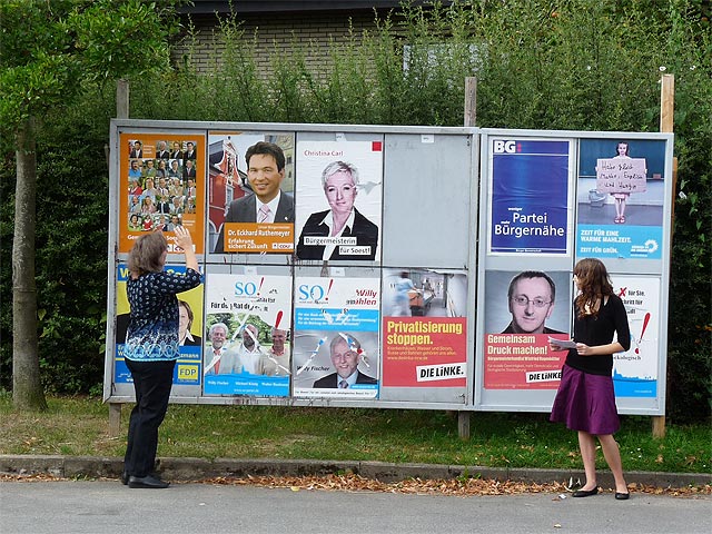 vor der Meiningser Plakatwand zur Kommunalwahl 2009